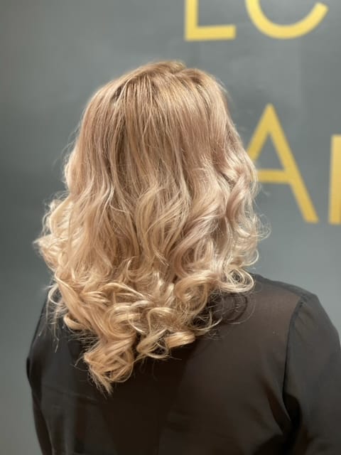 Blonde krullen voor de gouden letterwand in het salon